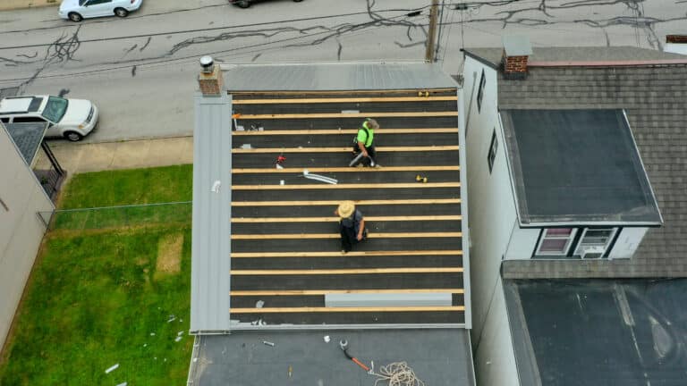Men installing a metal roof over shingles on a house